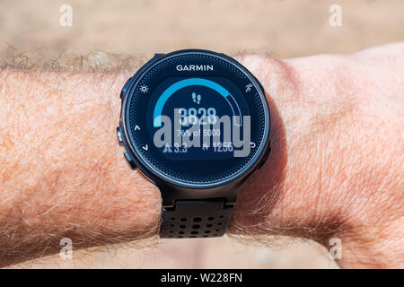 Garmin Smart Watch on male wrist displaying a step counter, distance traveled in kilometers and amount of calories burned Stock Photo