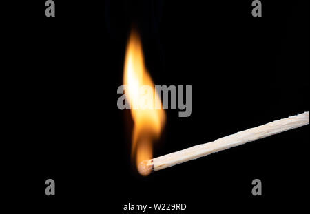 Curved flame of fire on a wooden match. Lighting matches at the moment when it explodes. Burning wooden match over black background. Macro shot. Copy Stock Photo