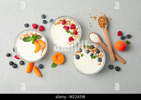 Flat lay composition with yogurt desserts and fruits on grey cement background Stock Photo