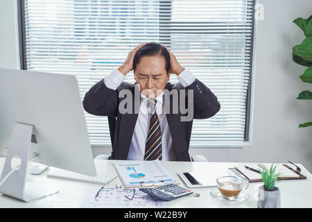 Overwhelmed asian businessman going crazy in office Stock Photo