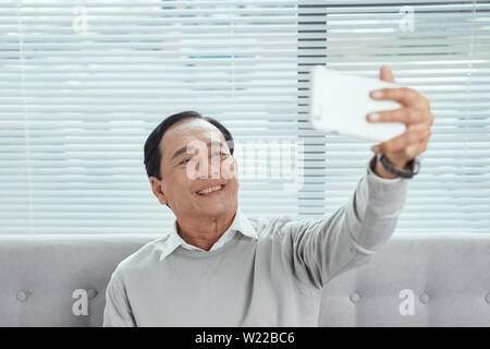 Happy Senior man Showing Toothy Smile While Taking Selfie Photo Using Mobile Phone