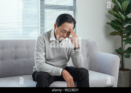 health care, stress, old age and people concept - senior man suffering from headache at home Stock Photo