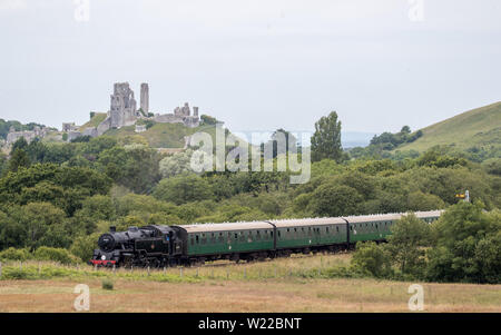 Steam locomotive BR Standard Class 4 80104, makes it's way past Corfe Castle as it travels along the Swanage railway in Dorset. Stock Photo