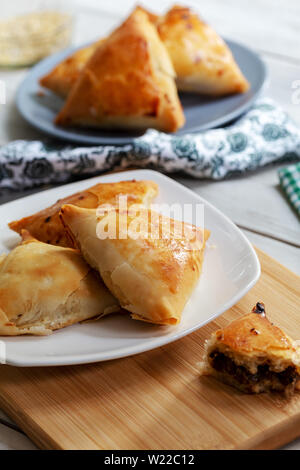 Puff pastry triangles filled minced meat, onion and spices Stock Photo