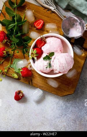 Strawberry ice cream in white bowl on a light stone or slate table. Free space for your text. Top view flat lay background. Stock Photo