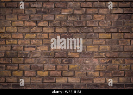 Wall made from red and sometimes colorful bricks of regular shapes and random distribution slotting together precisely. Closeup architecture. Stock Photo