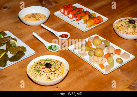 Meze Assorted Turkish Starters on a Wooden Table - Stuffed Vine Leaves, Pepper Rolls, Pickles, Hummus, Babaganoush Stock Photo