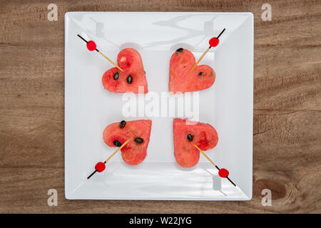 Slices of watermelon in the heart shape on vintage wooden table. Top view Stock Photo