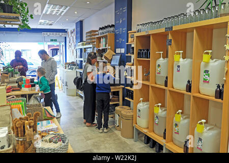 Woman child weighing and refilling containers shopping zero waste refill shop interior selling ethical sustainable products in Wales UK  KATHY DEWITT Stock Photo