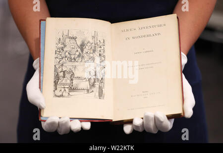 A Sotheby's employee handles a first edition of 'Alice's Adventures in Wonderland' by Lewis Carroll which will be included in Sotheby's upcoming English literature, history, children's books, and illustrations auction. Stock Photo