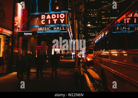 RADIO CITY MUSIC HALL: Night shoot of passersby and the neon nights of the Radio City Music Hall in New York - April 2019, New York, NY, USA Stock Photo