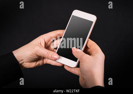 mobile phone in female hands on a black background Stock Photo