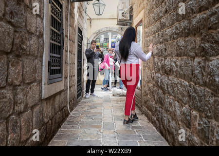 Montenegro, May 2nd 2019: Urban scene with man photographing woman in a narrow street of the Old Town of Budva Stock Photo