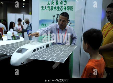 Dalian, China's Liaoning Province. 5th July, 2019. An exhibitor introduces a model of solar-powered boat to visitors during the 20th China Overseas Scholar Innovation Summit in Dalian, northeast China's Liaoning Province, July 5, 2019. The 20th China Overseas Scholar Innovation Summit kicked off here on Friday. Credit: Lyu Wenzheng/Xinhua/Alamy Live News Stock Photo