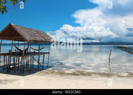 Stilt platform with hammocks over the water on a tropical beach in Raja Ampat on a sunny day. Stock Photo