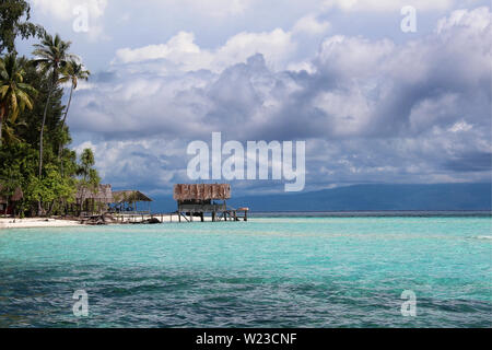 Old wooden platform on stilts over the blue, turquoise ocean with dramatic clouds in the background in Raja Ampat, Papua, Indonesia. Stock Photo