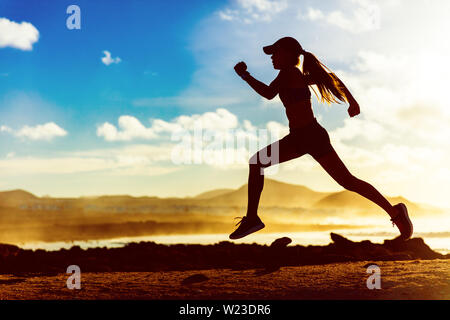 Silhouette of active healthy lifestyle athlete runner running in morning sunrise. Woman trail running on sunset ocean landscape sprinting with energy and speed in outdoor nature training cardio.