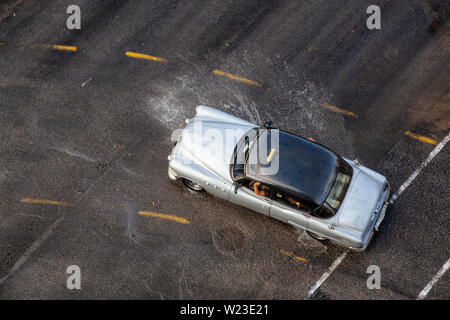 Havana, Cuba - May 29, 2019: Aerial view from above of an Old Car driving on the wet road after a rain pour. Stock Photo