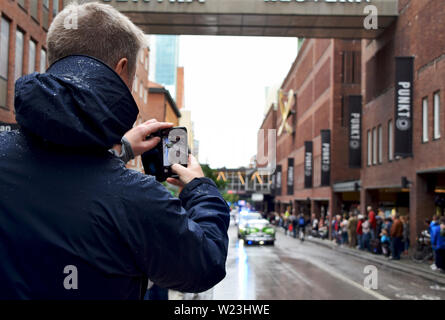 Man taking photos with smartphone of American cars cruising in Västerås city during Summer Meet - one of the biggest carshows in Europe Stock Photo