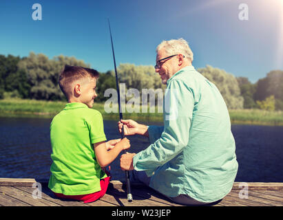 grandfather and grandson fishing on river berth Stock Photo