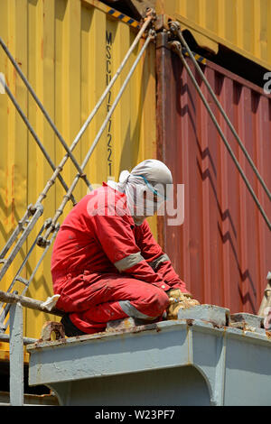 south atlantic ocean, international waters - january 14, 2014: a philippine sailor removing rust on deck of the containership msc alessia (imo 9225653 Stock Photo