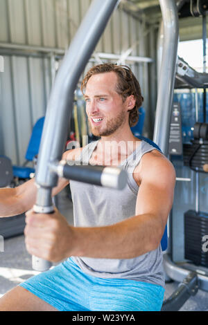 Gym fitness training. Male athlete training chest muscles on fitness equipment pec deck fly working out strength training indoors. Man working out pectoral muscles on fitness machine at gym center. Stock Photo