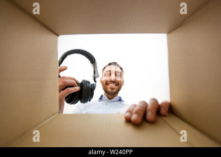 smiling man taking headphones out of parcel box Stock Photo