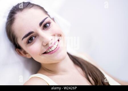 Portrait of smiling young woman sitting on chair in clinic, close-up. Stock Photo