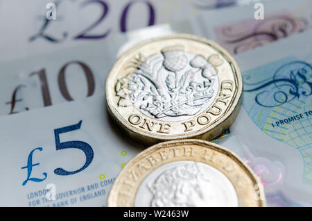 Macro photo of One Pound coins and the British pound banknotes of different denomination.