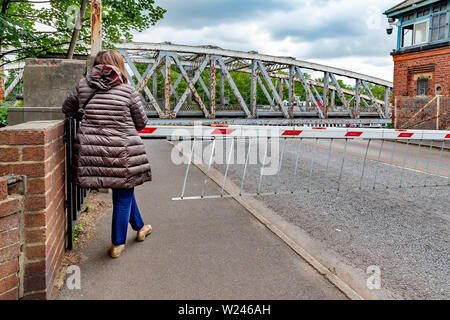 Woman waiting on the footpath at Stockton Heath swing bridge whilst a boat passes through