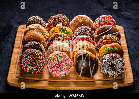 assorted donuts on wooden cutting board Stock Photo
