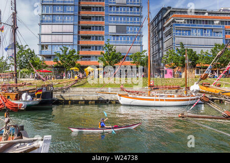 Canoe in between old ships in the harbor of Kiel, Germany Stock Photo