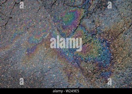 Close-up of an iridescent oil or gasoline spill on a wet asphalt, viewed from above. Top view. Stock Photo