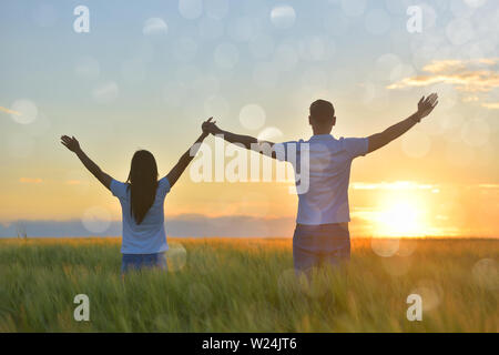 Young couple feeling free in a beautiful natural setting, in what field at sunset Stock Photo