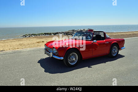 Classic Red Triumph TR4 Convertible Motor Car being driven along Seafront Promenade. Stock Photo