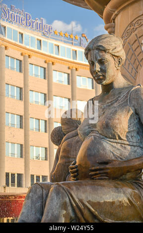 SKOPJE,NORTH MACEDONIA/AUGUST 22 2018: Statues of pregnant and nursing Mothers sit around an elaborate fountain, near to the Stone Bridge Hotel (backg Stock Photo