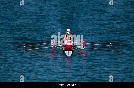 Four Male Rowers In A Quad Racing Boat With Synchronous Oar Stroke Stock Photo