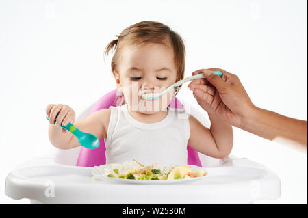 Mom feeding baby with spoon isolated on white studio background Stock Photo
