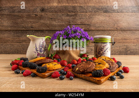 Chocolate cookies on wooden board with berries and ceramic vessels Stock Photo