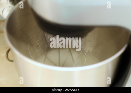 Whipping egg whites in professional kitchen mixer in a restaurant. Close-up whipped whites and sugar in a metal planetary blender bowl. Stock Photo