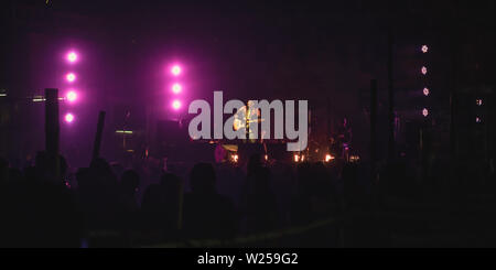 Kolkata India 1 May 2019: Guitarist performing on. Rock Concert venue with lit bright colorful stage lights and silhouette of fans or cheering crowd i Stock Photo