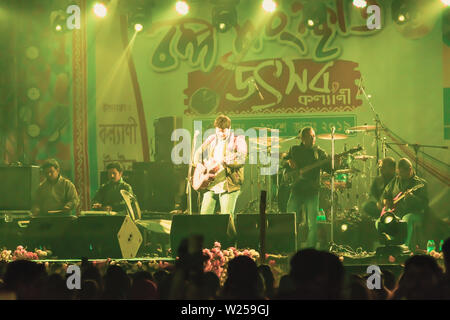 Kolkata India 1 May 2019 - Guitarist performing rock concert venue with lit bright colorful stage lights and fans or cheering crowd in front of it. Su Stock Photo