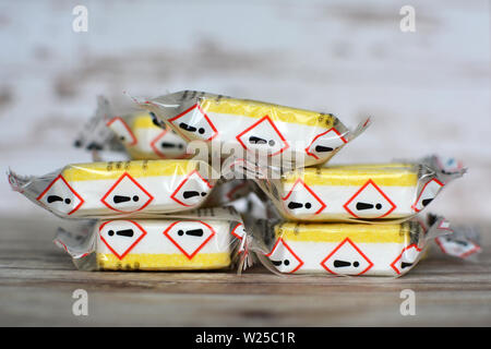 Yellow sealed laundry detergent or dishwasher cleaning tabs with warning label on package Stock Photo