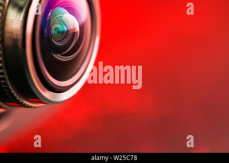 Camera lens with red backlight. Side view of the lens of camera on red background. Camera Lens close Up. Optics Stock Photo