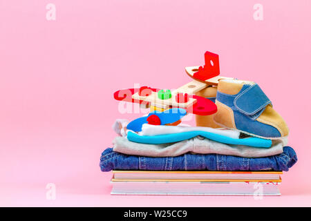 Donation concept. Kid toys, books and clothes for donate or charity on pink background Stock Photo