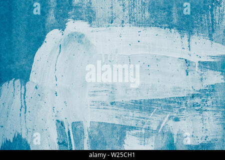 White paint stains on blue canvas. Drips of white paint on the blue wall. Painted dirty concrete wall. Smeared wall in whitewash, stained plaster. Abs Stock Photo