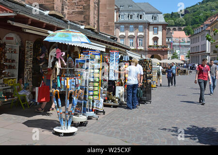 Tourists looking at souvenir shops offering various local trinkets at marketplace on a sunny day in Heidelberg, Germany Stock Photo
