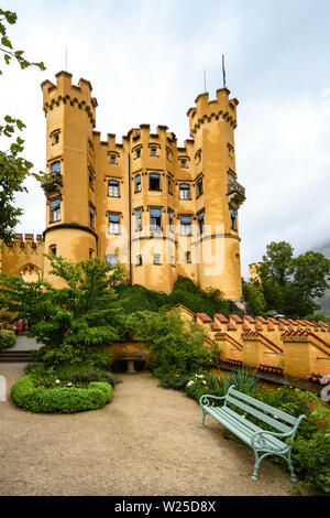 BAVARIA, GERMANY - JUL 2017: View of the Royal castle against the clouds. Well-kept courtyard and a bench to relax in the foreground. Stock Photo