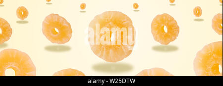 dried pineapple fruit levitating over yellow background, panoramic image, creative minimalism Stock Photo