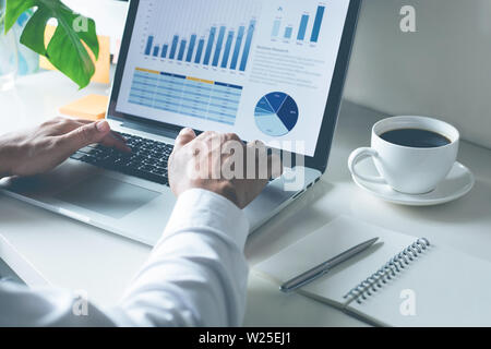 Young businessman typing computer laptop with graph chart for work Stock Photo